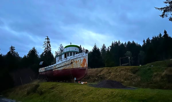 a rusty boat named Margaret sits on a small grassy hill.