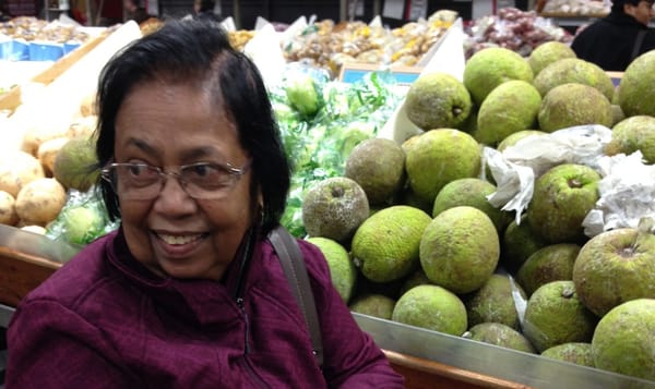 a photo of my achchi in a busy produce market, her face full of pleasant surprise.