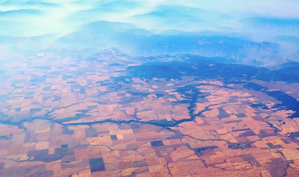 a photo of the countryside as seen from the window of a plane. the upper third of the picture contains slowly undulating hill