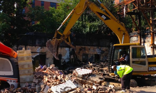 a piece of heavy machinery clears wreckage from a demolition site