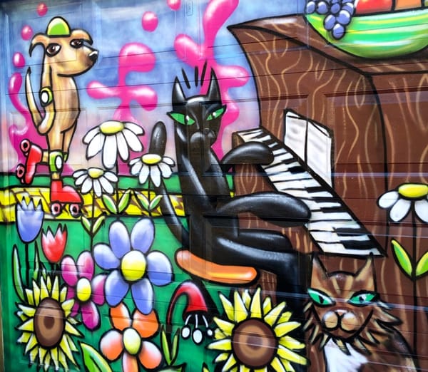 a spray paint mural of a few animals doing fun stuff in a field of flowers