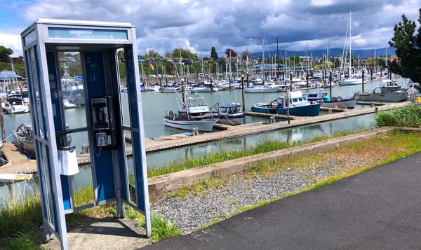 a phone booth on the edge of a walkway at a marina