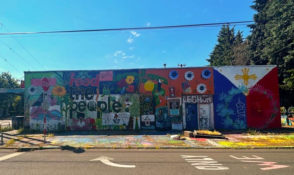 a painted mural on the side of a building that reads "feed the people" surrounded by smaller painted artwork