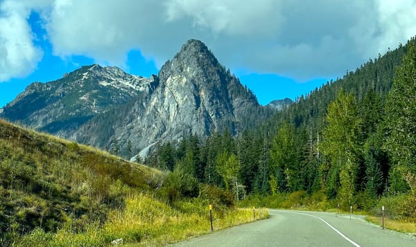 a winding road passes in front of a large granite mountain outside snoqualmie pass