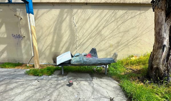 the itinerant, a sculpture of a man sleeping on a bench with a newspaper covering his face