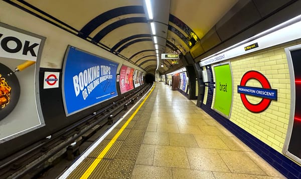 the mornington crescent station tube stop for the london underground. the yellow tile and flooring is offset by ads covering 