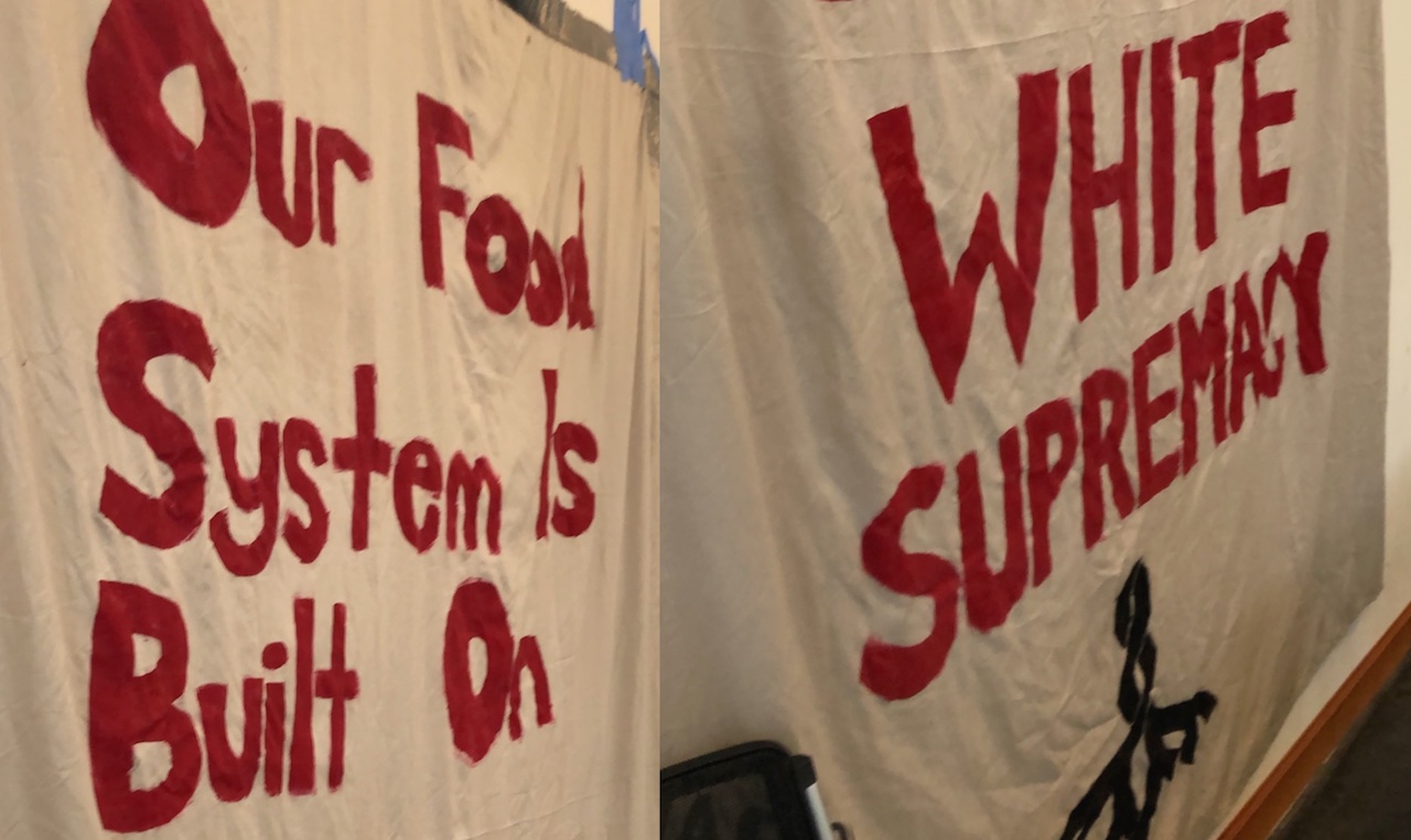 a hand-painted banner that read "Our Food System is Built on WHITE SUPREMACY"