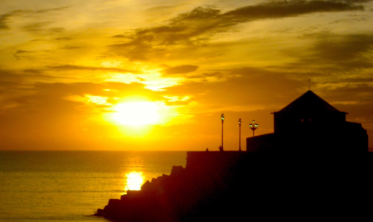 a photo of a sunset on the rocky shores of Cádiz, Spain.