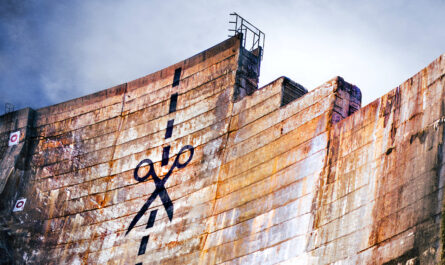 a dam with graffiti painted to look like scissors and a dotted line, indicating where to cut