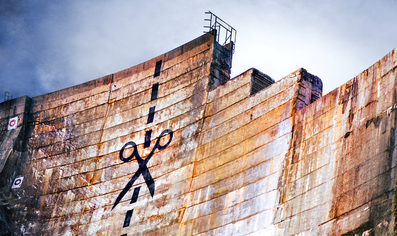a dam with graffiti painted to look like scissors and a dotted line, indicating where to cut