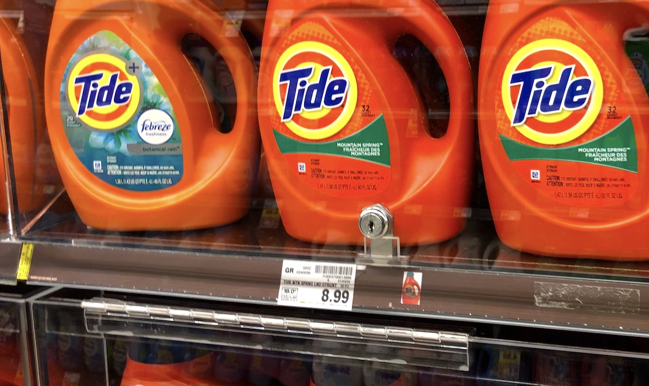 a row of laundry detergent locked up behind clear plastic