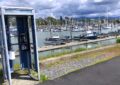 a phone booth on the edge of a walkway at a marina