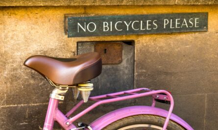 a pink bicycle parked under a sign that says no bicycles