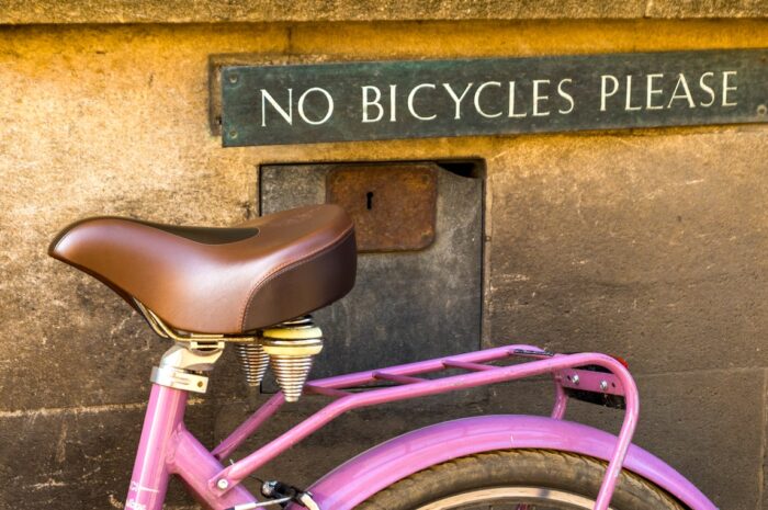 a pink bicycle parked under a sign that says no bicycles