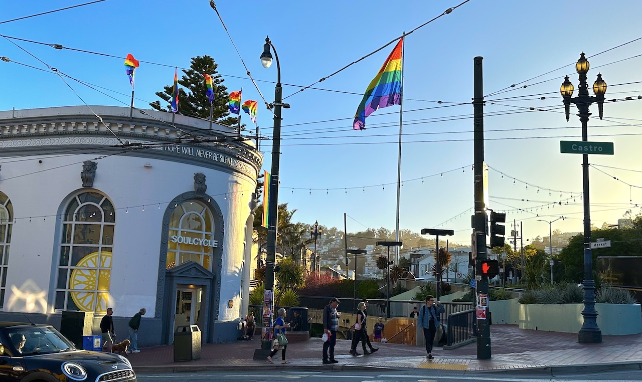 a couple rainbow flags flapping in the wind outside a soul cycle in the castro
