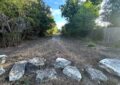 a path into the woods with large rocks strewn across the entrance