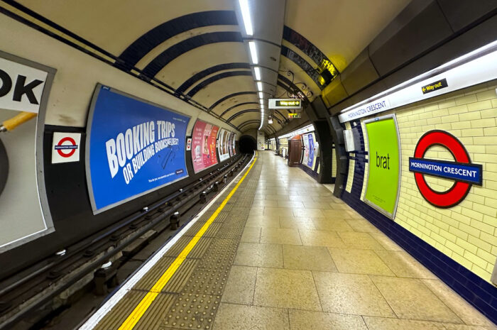 the mornington crescent station tube stop for the london underground. the yellow tile and flooring is offset by ads covering most of the surfaces