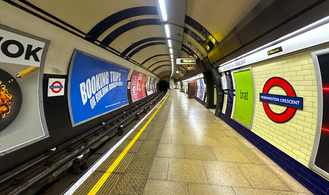 the mornington crescent station tube stop for the london underground. the yellow tile and flooring is offset by ads covering most of the surfaces