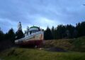 a rusting boat sits on land - a small hill next to a taller hill